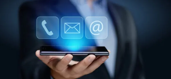 Contact entreprise avec téléphone, email et arobase affichés au-dessus d’un smartphone